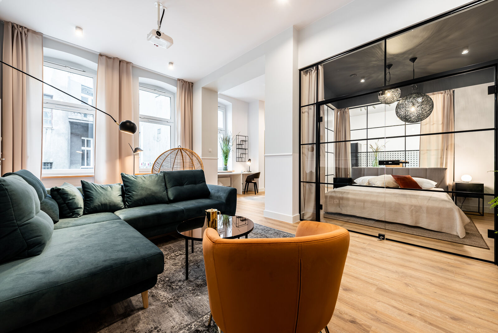 Living room with a glass-walled bedroom in a Wellcome Home apartment